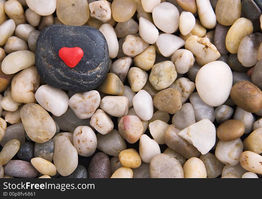 Red candy heart on a black stone surrounded by gravel