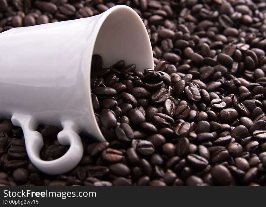 Coffee beans spilling out of a white coffee cup