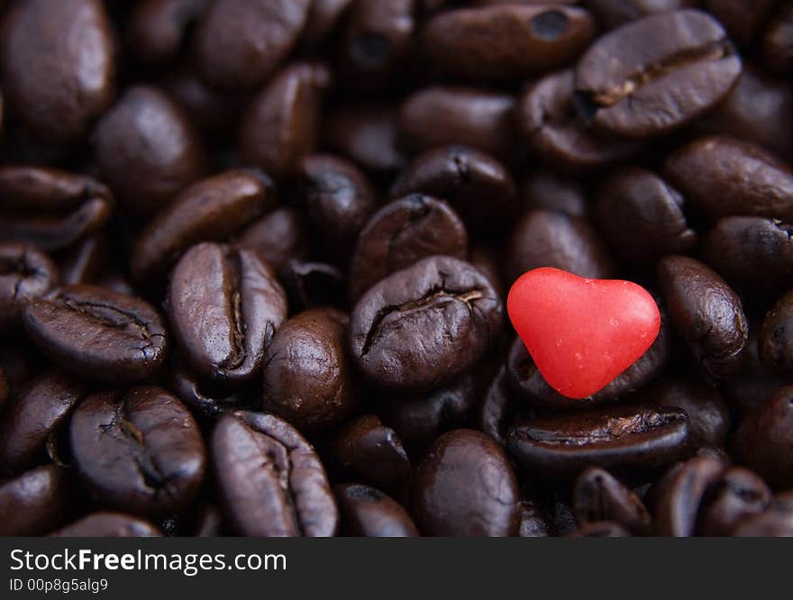 Close up of a red candy heart in coffee beans