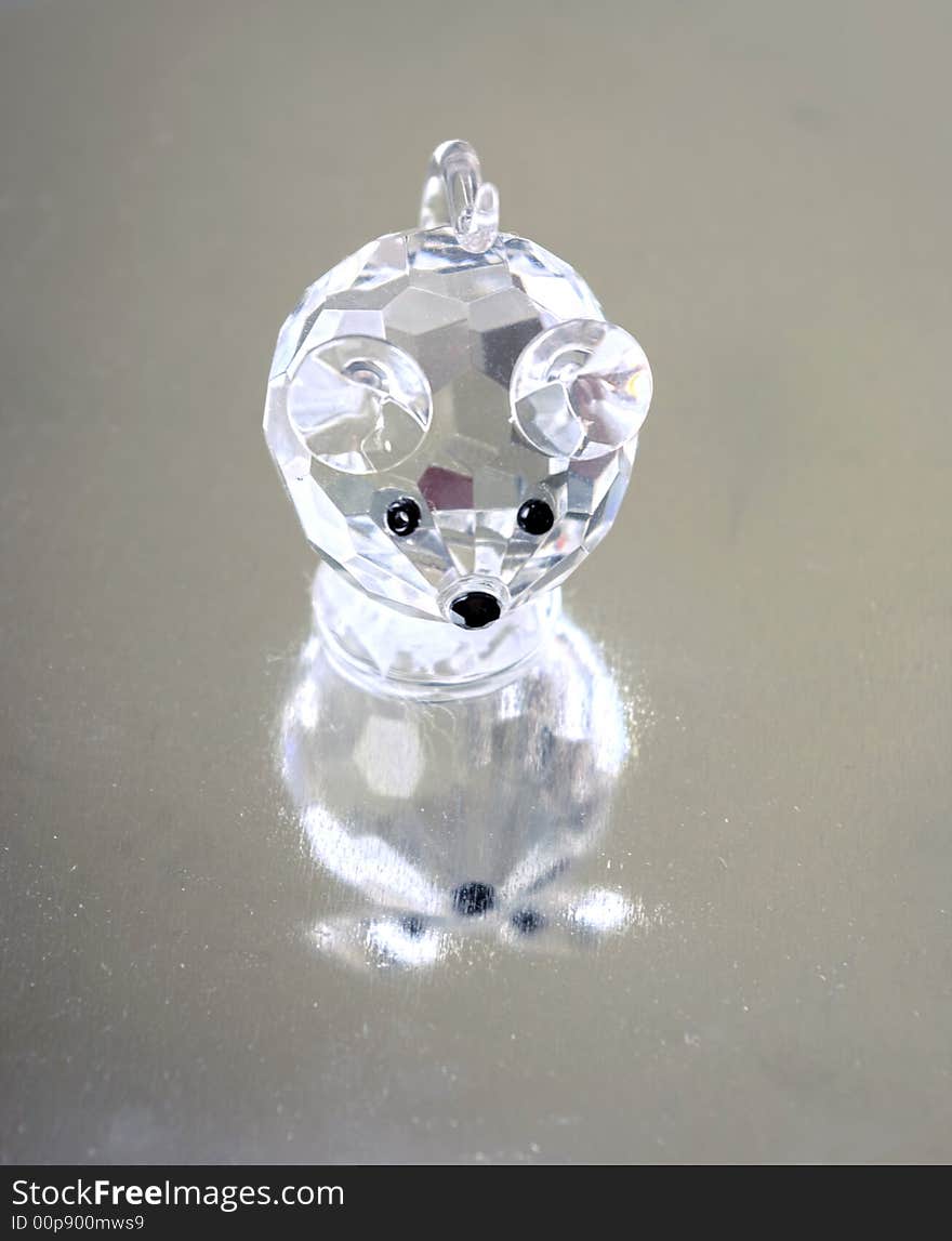 A small souvenir in the form of a glass mousy. Reflection from a metal ridge surface is visible.