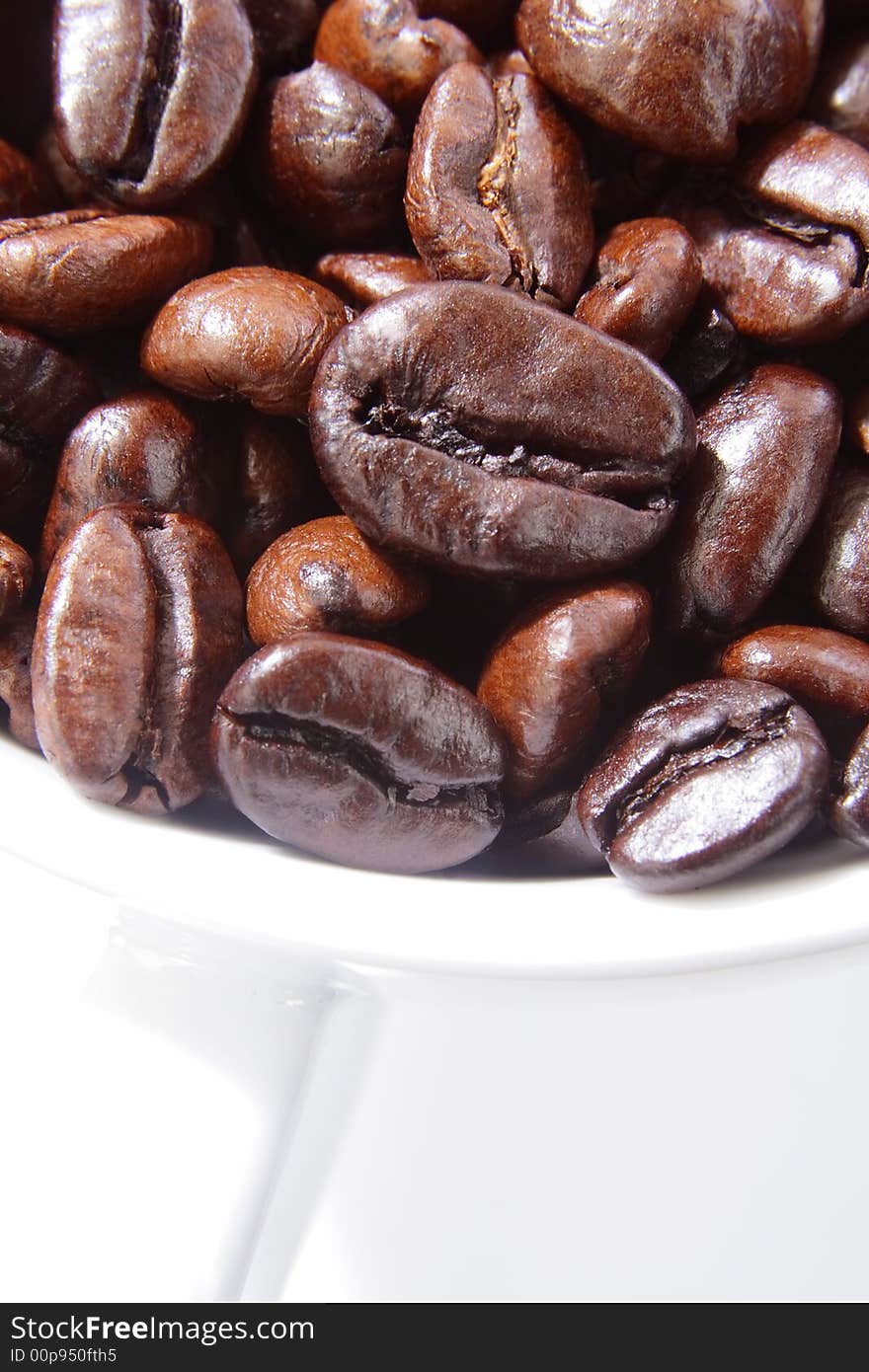 Close up of roasted coffee beans in a white cup. Close up of roasted coffee beans in a white cup.