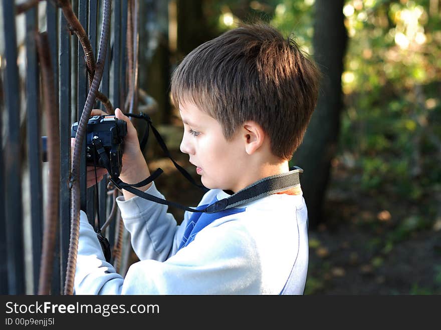 Boy concentrated holds a black digital camera in hands. Boy concentrated holds a black digital camera in hands