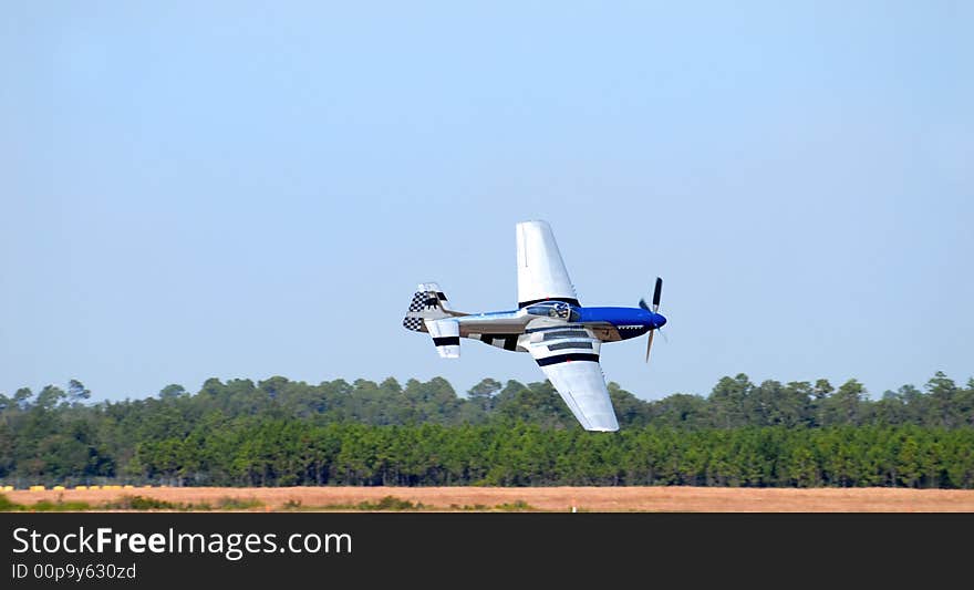 A World War 2 P-51 Mustang flying low to the ground at high speed. A World War 2 P-51 Mustang flying low to the ground at high speed