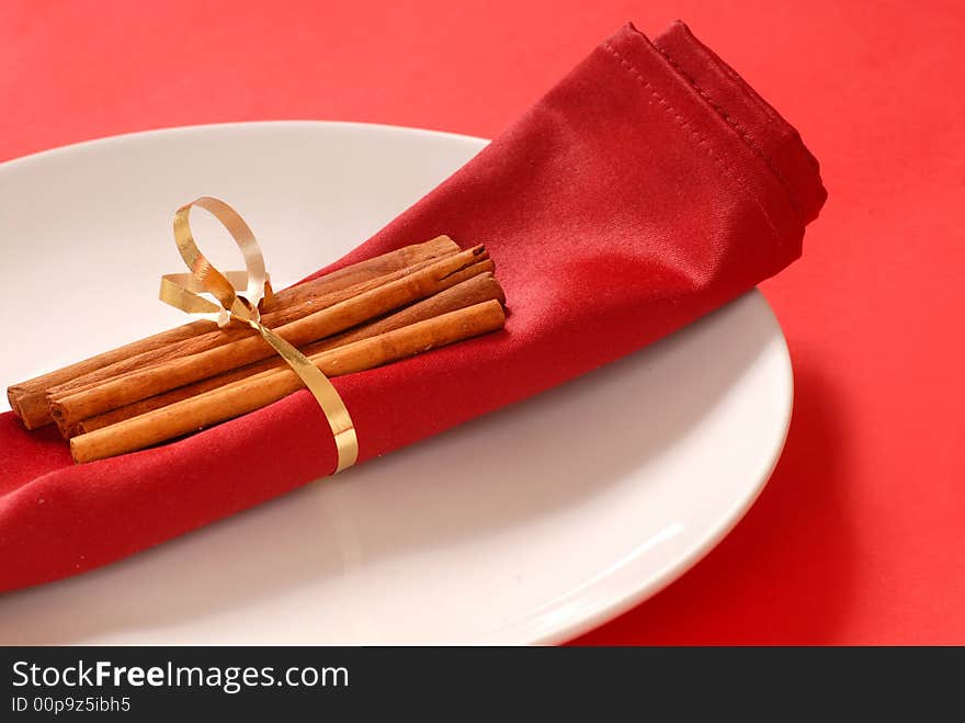 Red Napkin On A White Plate With Cinammon Sticks