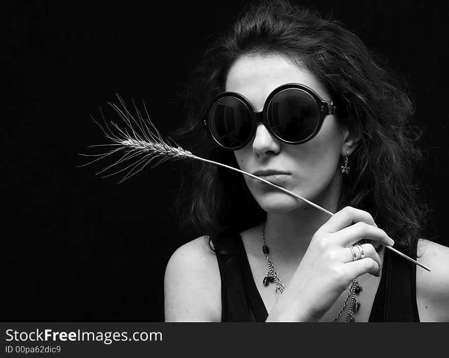 Beautiful brunette on black background with glasses and wheat. Beautiful brunette on black background with glasses and wheat