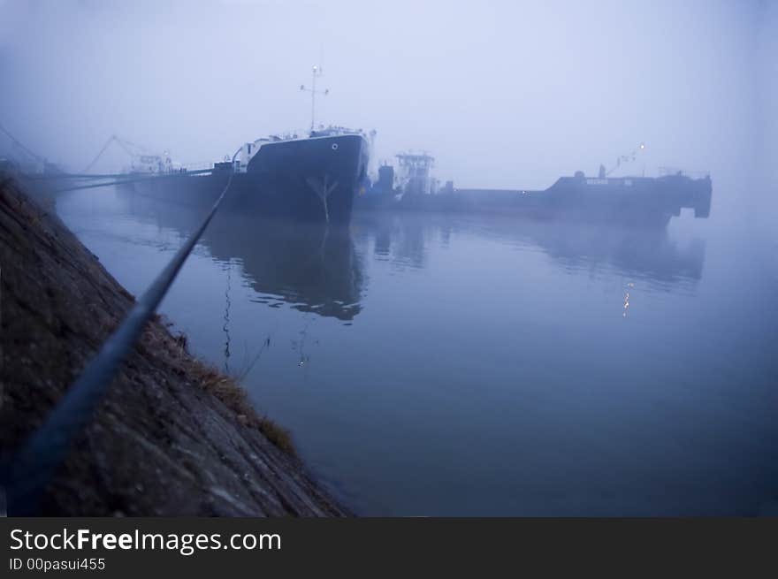 Ship tied with steel wire cable for the stone in the harbor fog. Ship tied with steel wire cable for the stone in the harbor fog