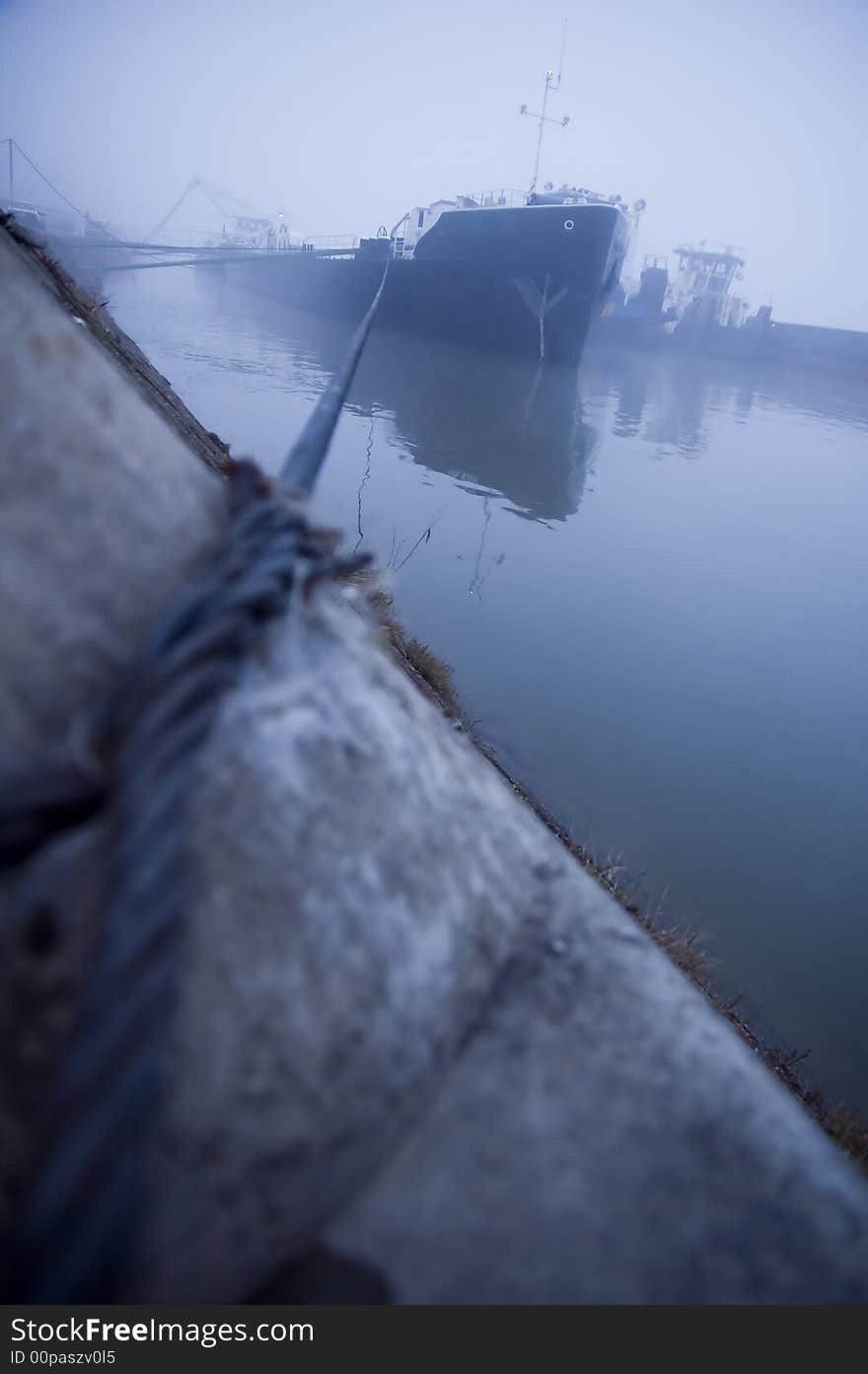 Ship tied with steel wire cable for the stone in the harbor fog. Ship tied with steel wire cable for the stone in the harbor fog