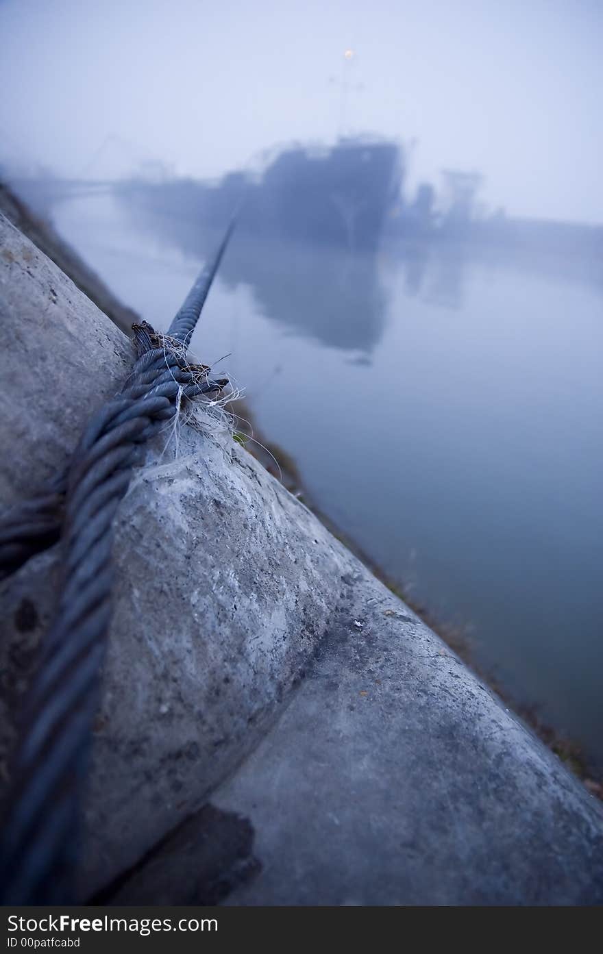 Ship tied with steel wire cable for the stone in the harbor fog. Ship tied with steel wire cable for the stone in the harbor fog