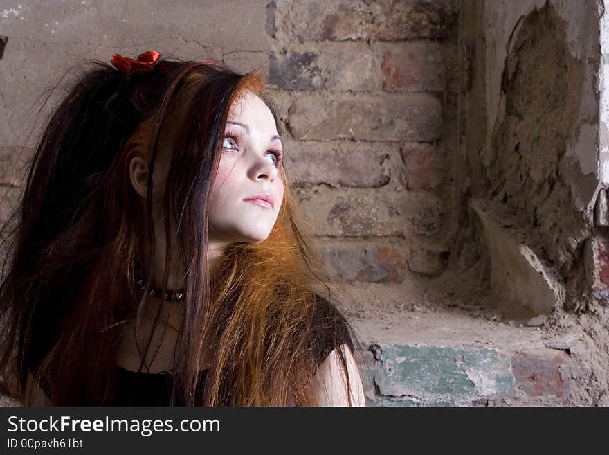 The attractive girl in Gothic style on a background of a brick wall