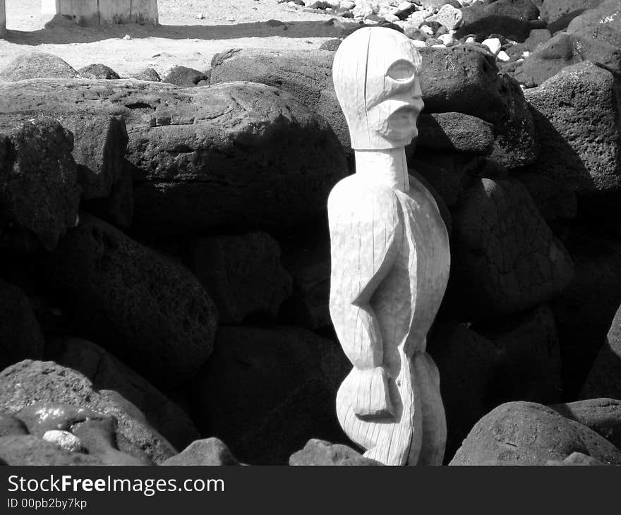 Black and white picture of a Hawaiian Tiki idol tucked in to a bed of volcanic rock. Black and white picture of a Hawaiian Tiki idol tucked in to a bed of volcanic rock.