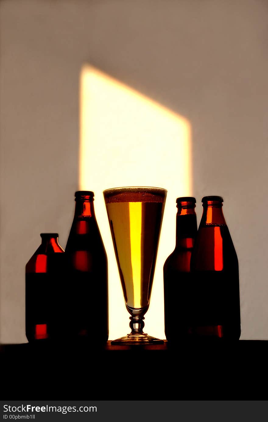 A tall pilsner bottle filled to the brim with beer, stands along with a grouping of unopened bottles
of beer placed to create a frame effect for the beer glass. A tall pilsner bottle filled to the brim with beer, stands along with a grouping of unopened bottles
of beer placed to create a frame effect for the beer glass.