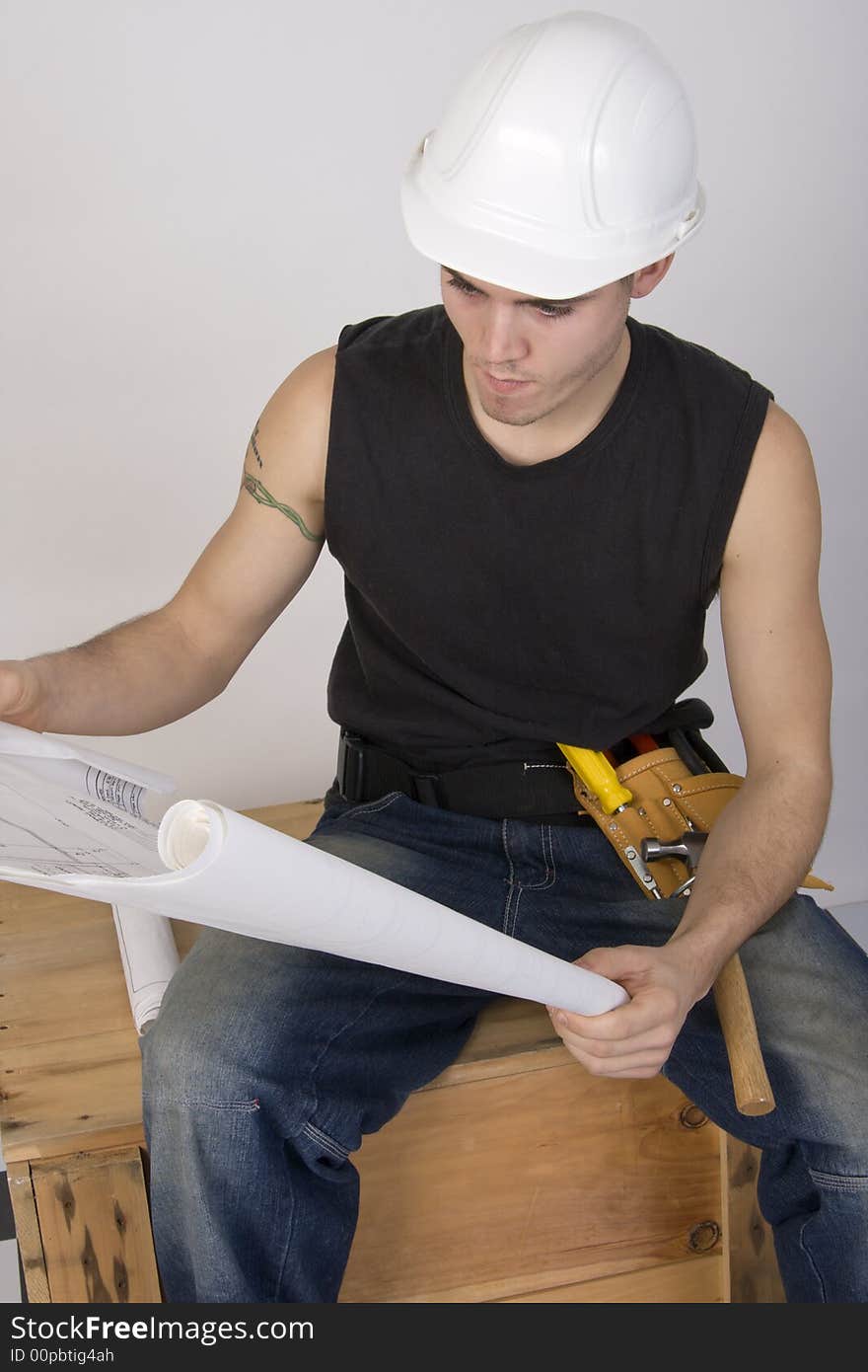 Young man in hard hat looking at blueprints. Young man in hard hat looking at blueprints