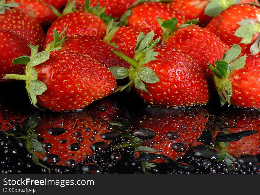 Fresh strawberries with water drops on wet black surface