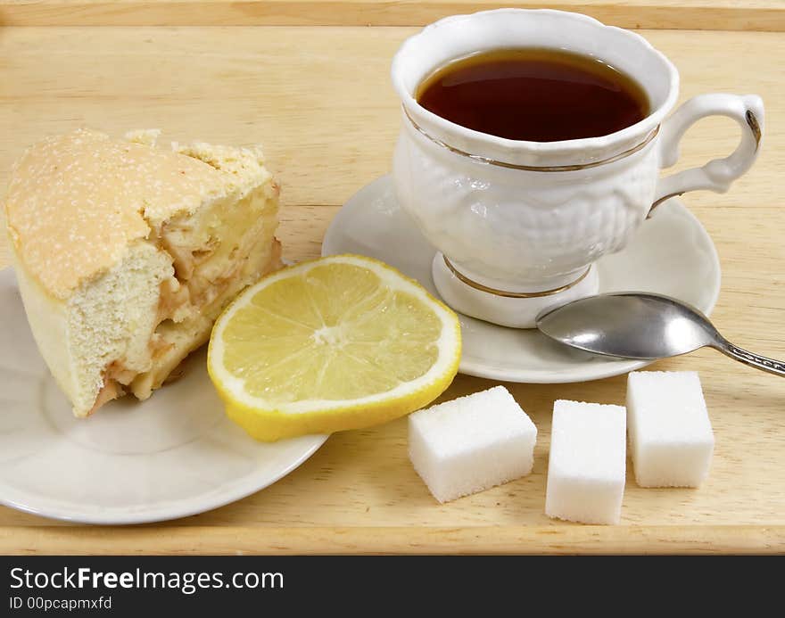 Cup of tea on a tray with a lemon and a biscuit