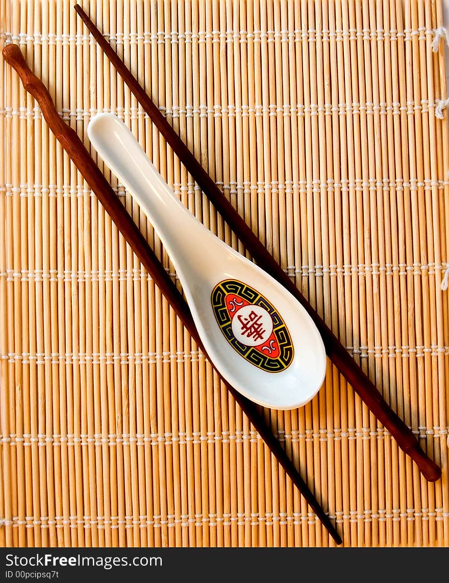 A  soup spoon and chopsticks on bamboo used for rolling sushi. A  soup spoon and chopsticks on bamboo used for rolling sushi.