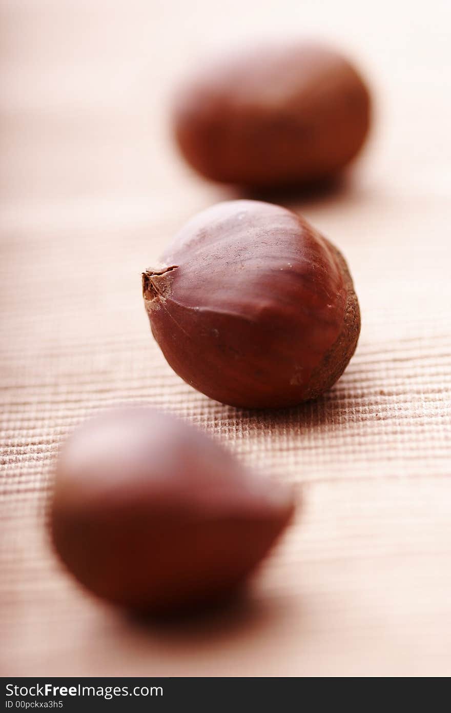 Chesrnuts lined up on cloth, focus on the middle one. Chesrnuts lined up on cloth, focus on the middle one