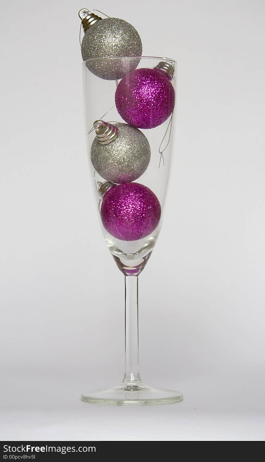 Four purple and silver Christmas baubles in a champagne glass