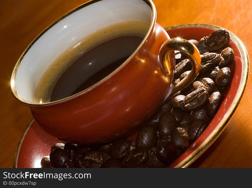 A coffee cup and sourcer. The sourer is filled with coffee beans. A coffee cup and sourcer. The sourer is filled with coffee beans.