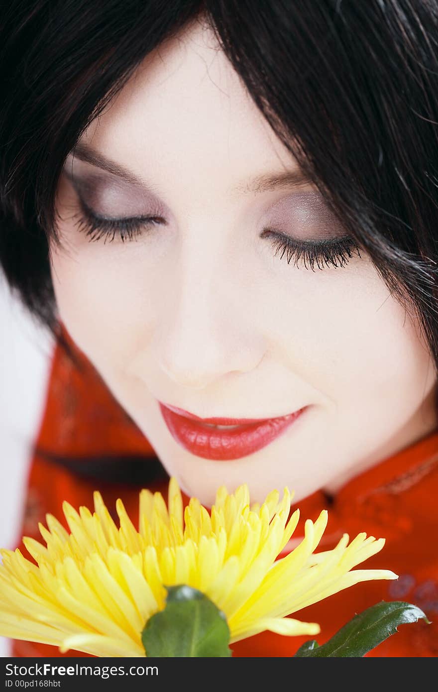 Close-up portrait of brunette with white skin smelling yellow flower. Close-up portrait of brunette with white skin smelling yellow flower