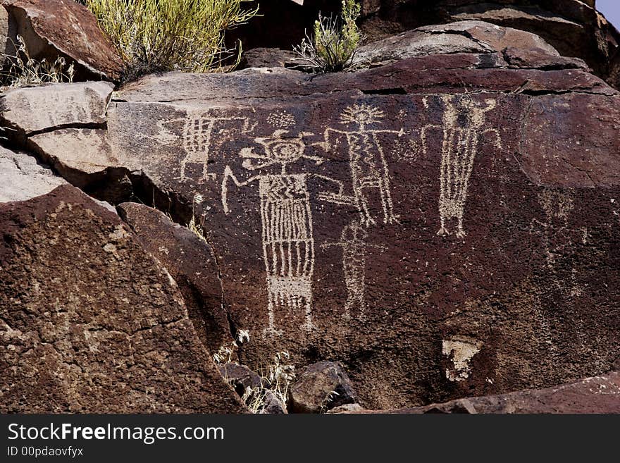 Native American rock art petroglyph of several anthropomorphic like figures carved into desert varnish covered rock in Little Petroglyph Canyon of the Coso Range in California. Native American rock art petroglyph of several anthropomorphic like figures carved into desert varnish covered rock in Little Petroglyph Canyon of the Coso Range in California