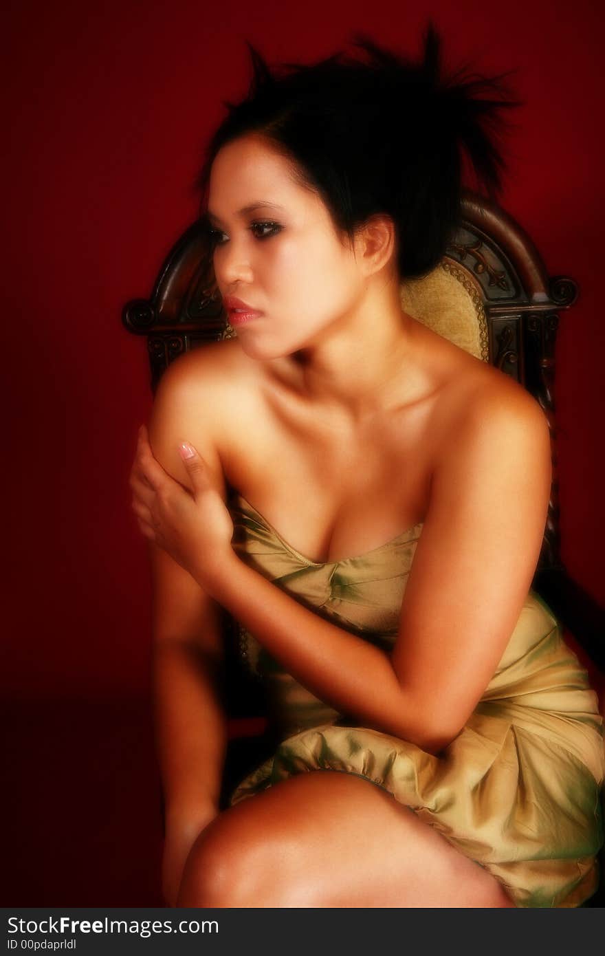 Beautiful twenty something Asian Indonesian mixed womn in gold formal dress on crimson red background. Beautiful twenty something Asian Indonesian mixed womn in gold formal dress on crimson red background.