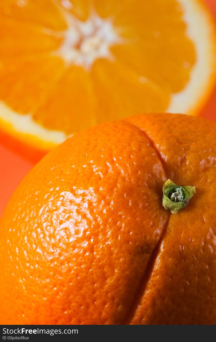 Vertical photo of whole orange in foreground with sliced orange in background. Vertical photo of whole orange in foreground with sliced orange in background