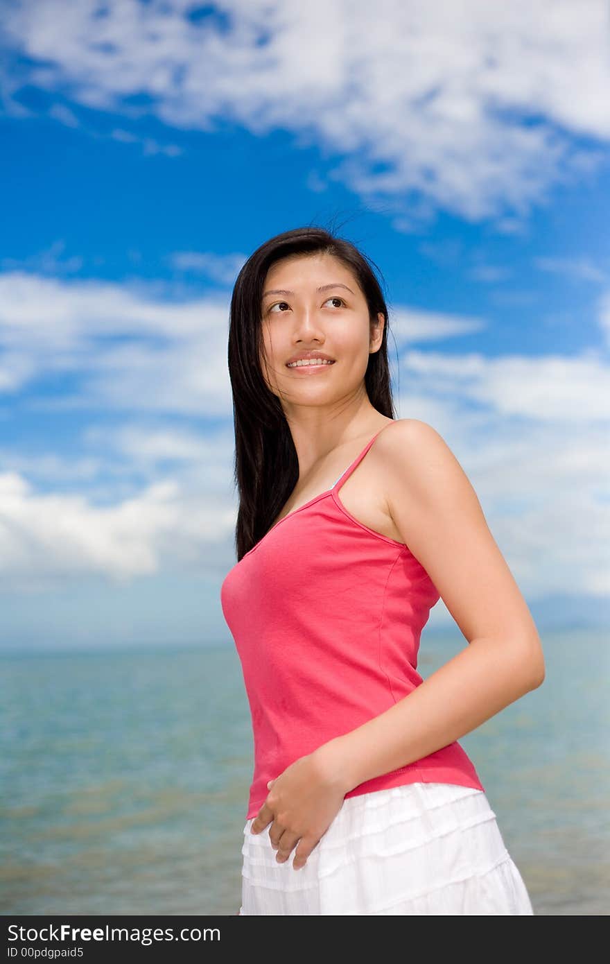 Woman smiling looking far with red top and white skirt stand by the sea. Woman smiling looking far with red top and white skirt stand by the sea