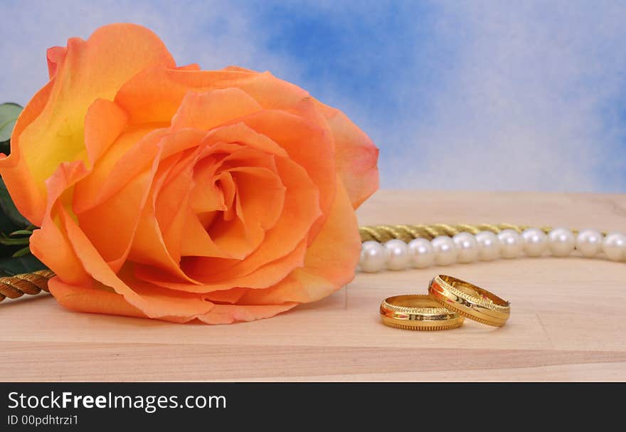 Rose With Wedding Rings and Pearls on Blue Background. Rose With Wedding Rings and Pearls on Blue Background