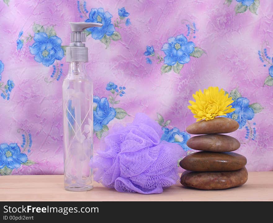 Massage Stones and Purple Bath Sponge on Pink Floral Background. Massage Stones and Purple Bath Sponge on Pink Floral Background