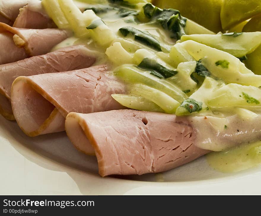 Coked ham rolls with stem cabbage on a white plate