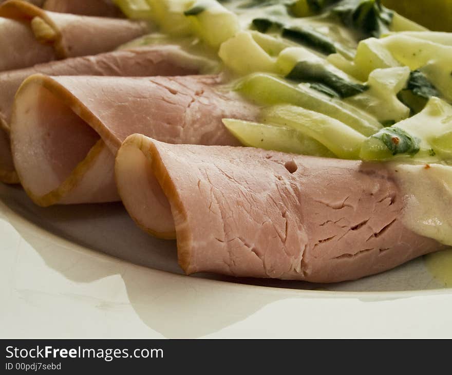 Coked ham rolls with stem cabbage on a white plate