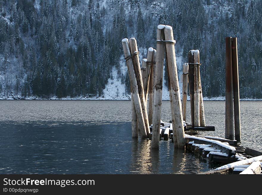 Old boat dock pilings dusted with snow in a mountain lake. Horizontal frame. Old boat dock pilings dusted with snow in a mountain lake. Horizontal frame.