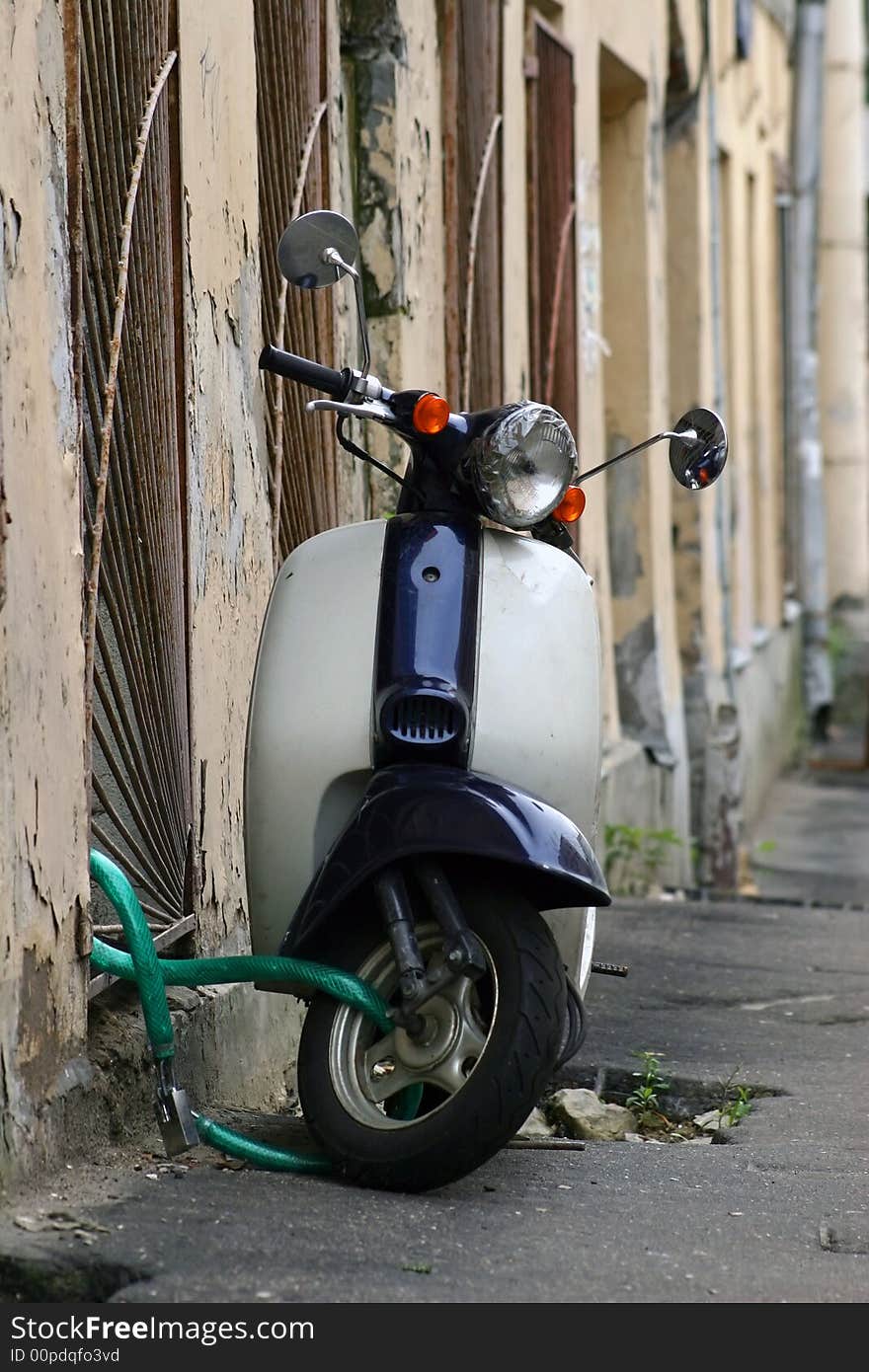 Old scooter, parked at a wall of a house