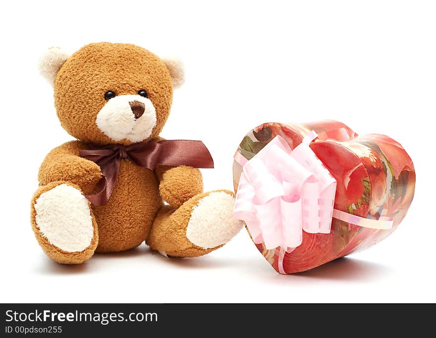 Classic brown Teddy Bear with heart-shaped present. Isolated on white background. Focus on Teddy Bear.