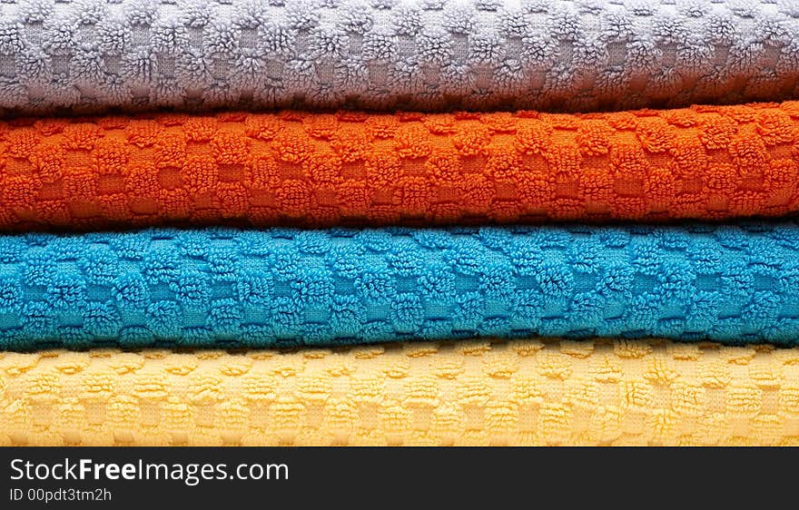 Multicolour towels rolls: gray, orange, blue, yellow. Close-up. Multicolour towels rolls: gray, orange, blue, yellow. Close-up.