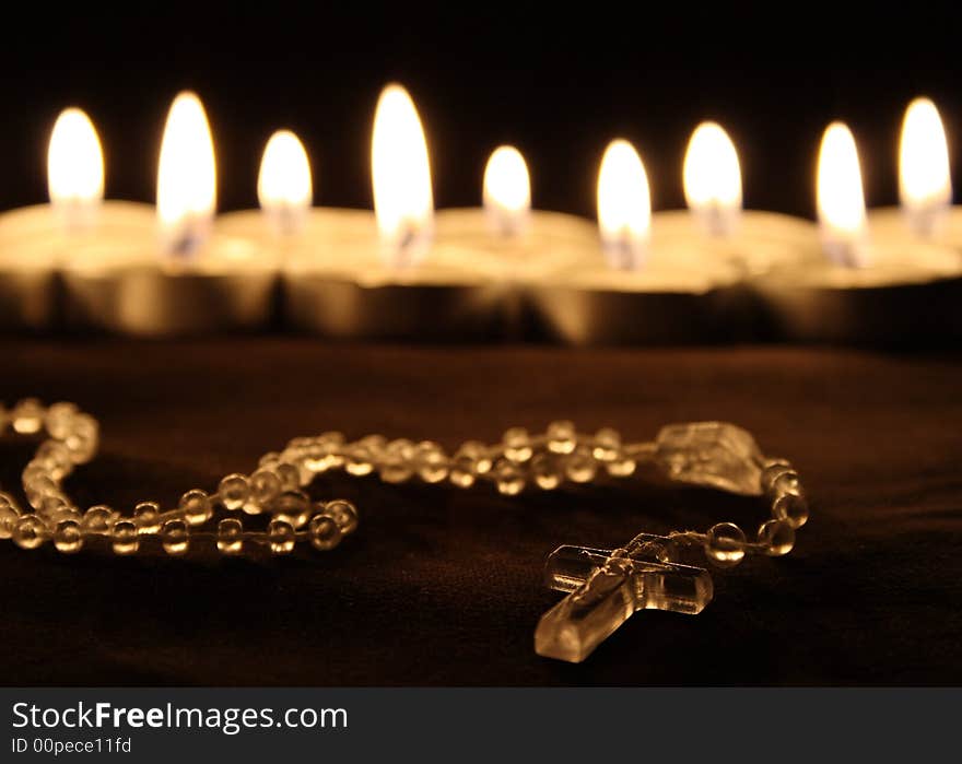 A crucifix in front of a row of candles. A crucifix in front of a row of candles