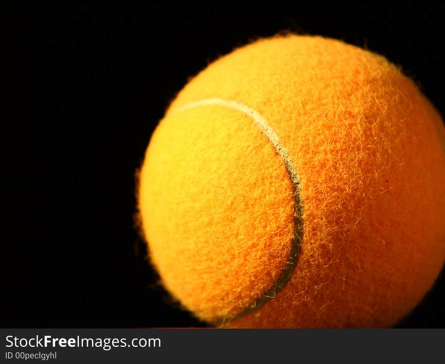 Orange tennis ball on black background