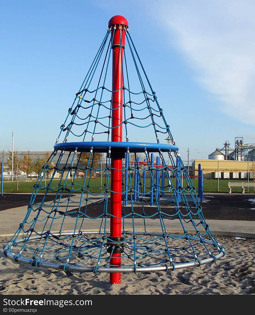 A children's climber in a park with industry in the background. A children's climber in a park with industry in the background.