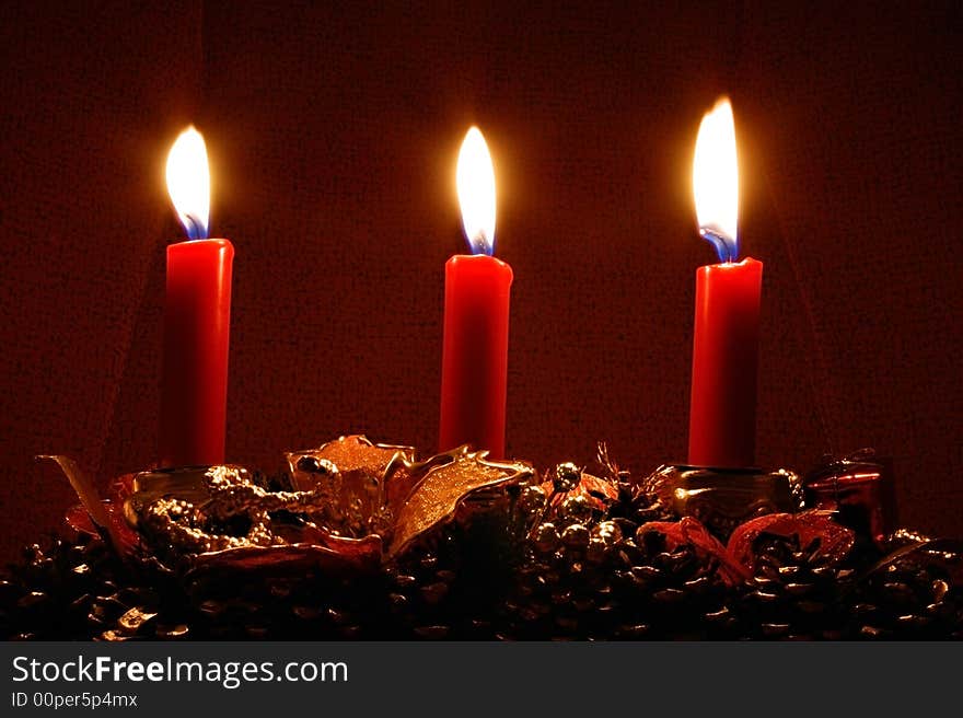 Three candles burning in the dark on christmans decorations - christmas theme