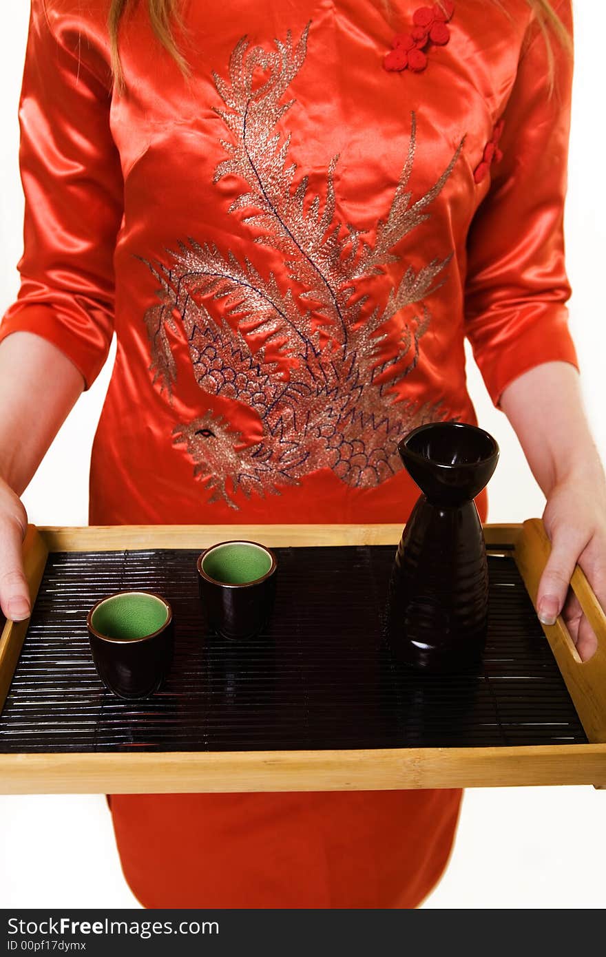 Body of an asian woman wearing orange satin culture attire holding a tray with a sake cups and jug. Body of an asian woman wearing orange satin culture attire holding a tray with a sake cups and jug