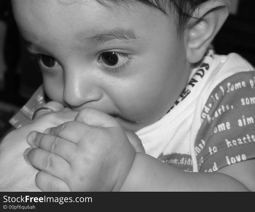 Seven month old boy holding his mother's hand near his mouth. Seven month old boy holding his mother's hand near his mouth