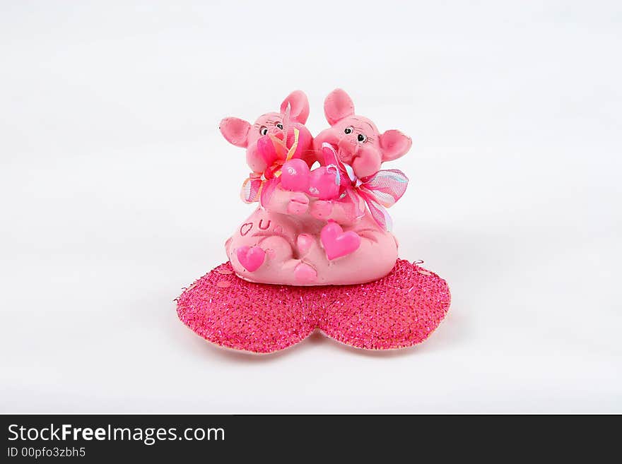 Two pink pigs sitting on heart and holding heart