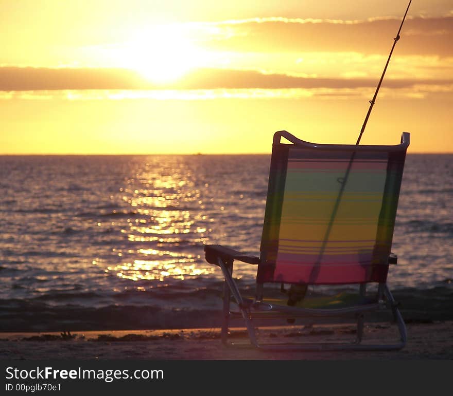 Fishing pole and beach chair at sunset