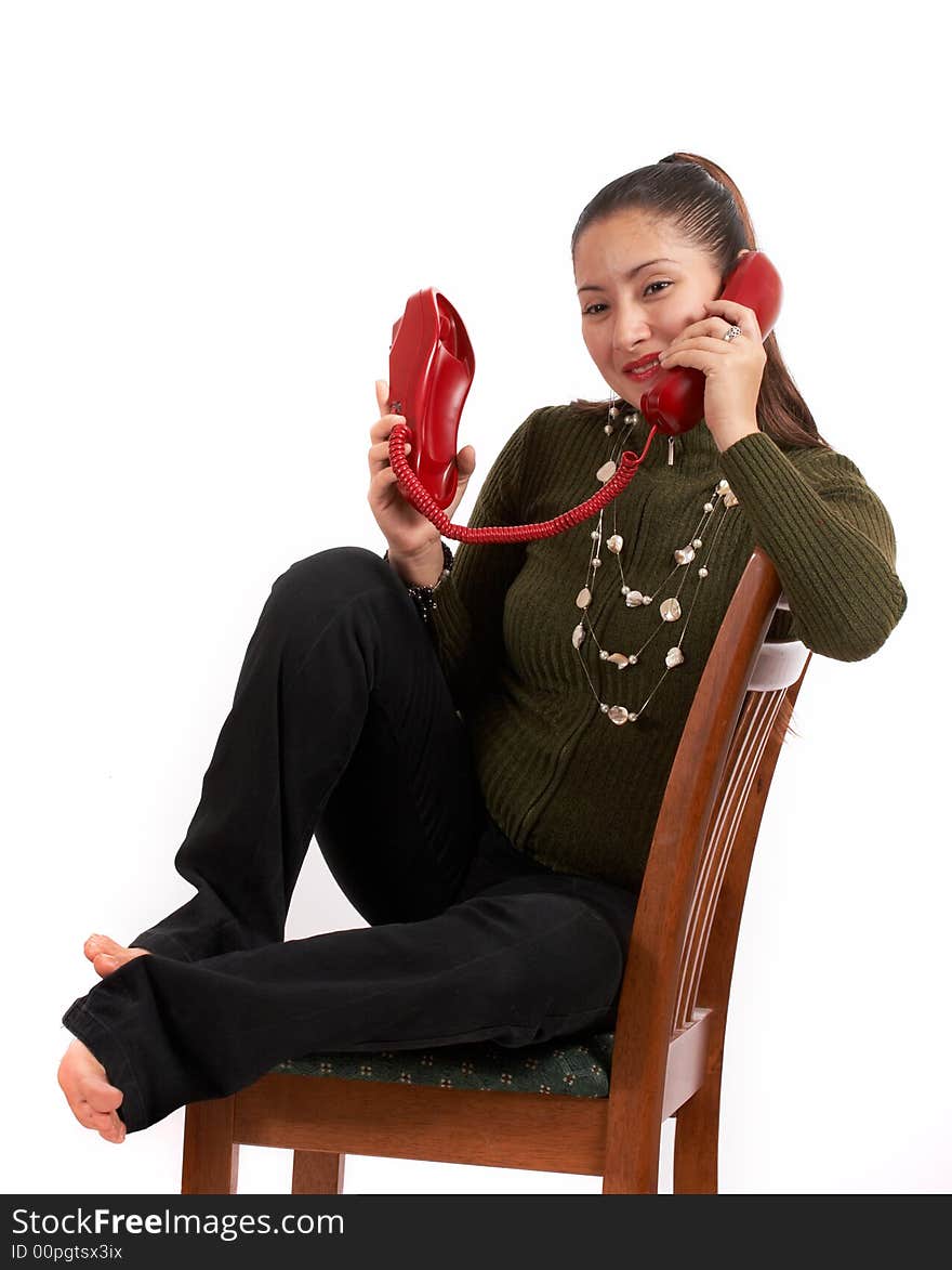 A young female talking on the phone while sitting on the chair. A young female talking on the phone while sitting on the chair