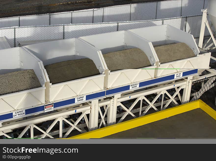 Bins of rock that drop onto a conveyer belt underneath and into the mixing machine. Bins of rock that drop onto a conveyer belt underneath and into the mixing machine