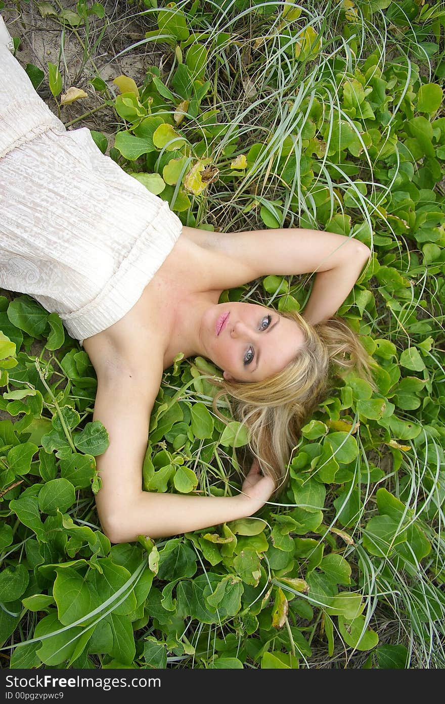 Beautiful girl lying in the grass at the beach. Beautiful girl lying in the grass at the beach