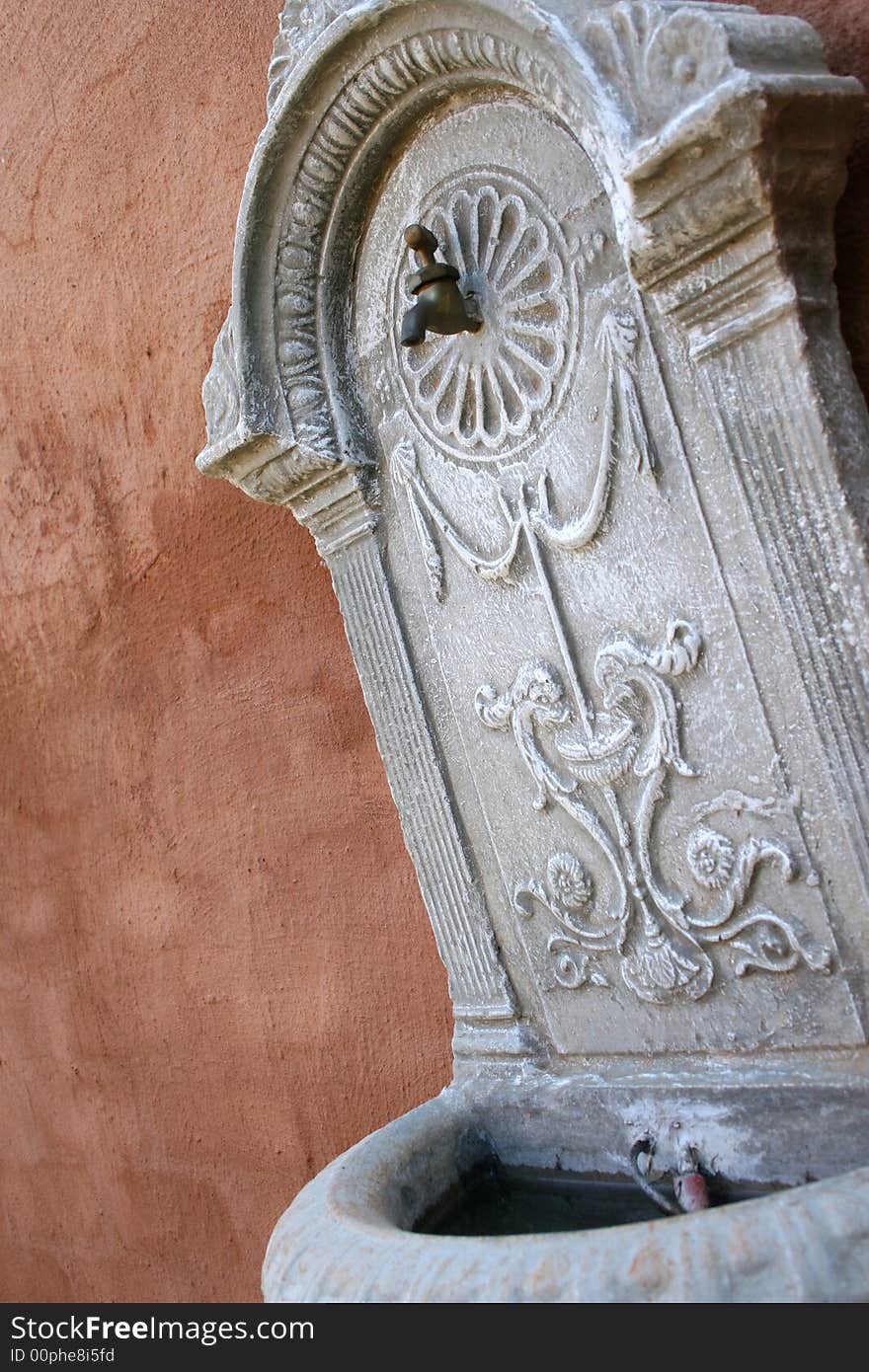 Outdoor Fountain against a brown wall in a garden