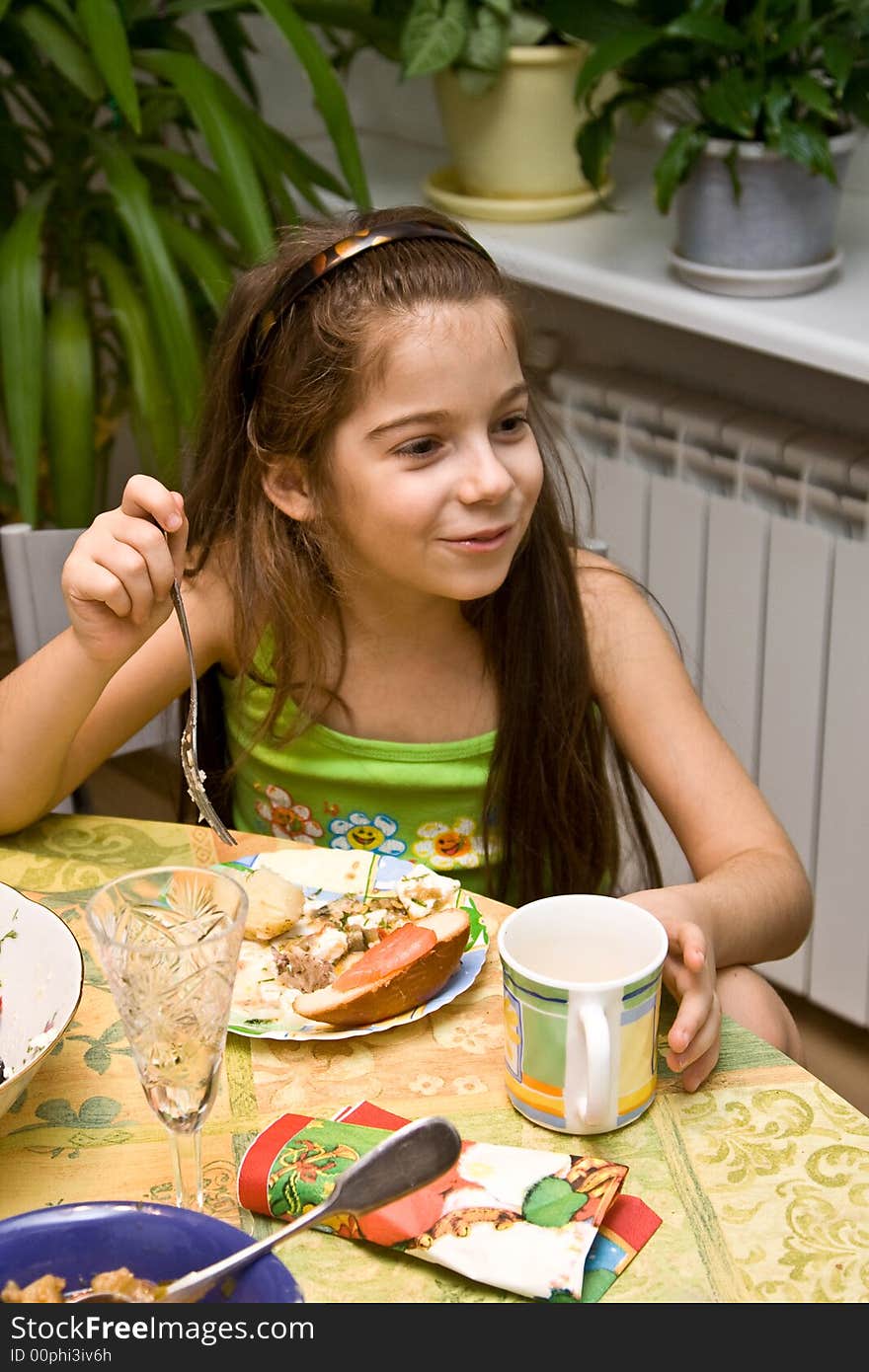 The girl sits at a table with meal and eats