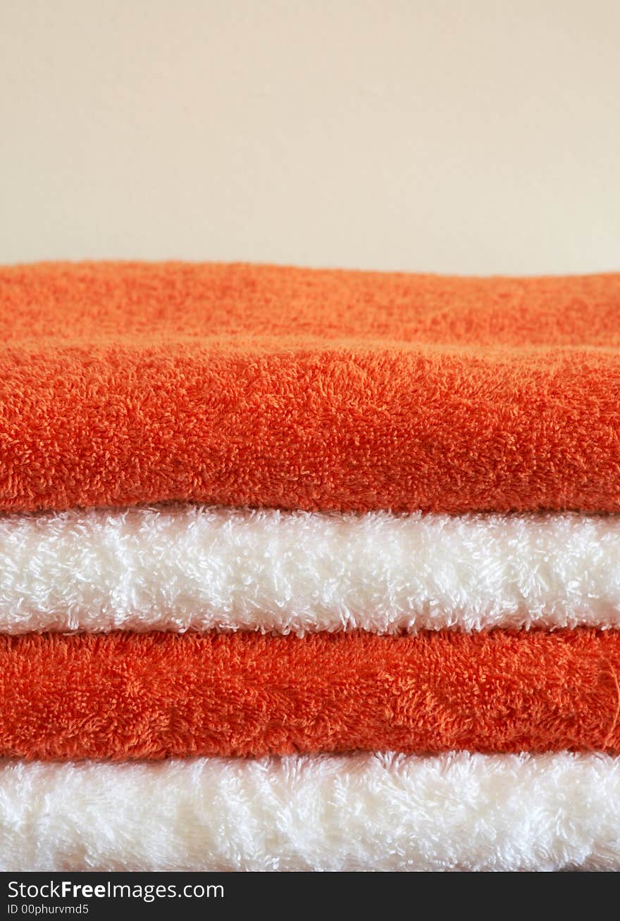 Stack of white and orange fluffy towels on light background. Stack of white and orange fluffy towels on light background