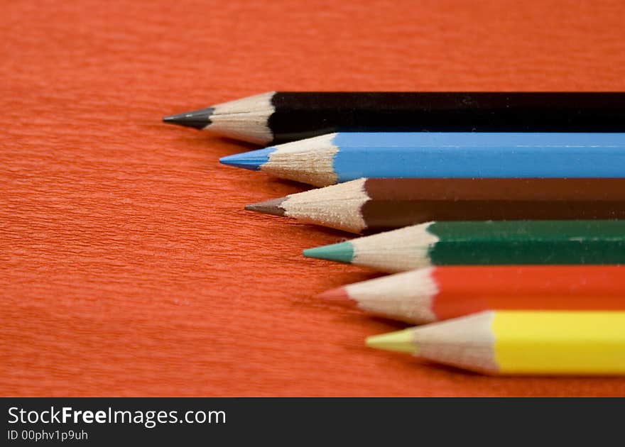 Six colored pencils over red background